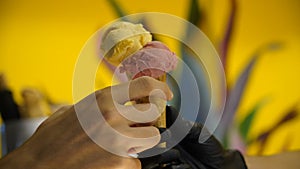 Seller in apron holding ice cream in a waffle cone, close-up. Selling ice cream in a shop