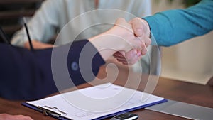 Seller and buyer shaking hands and sitting at table during deal in dealership office spbas.