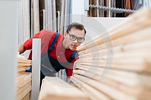 seller of the floor coverings store choosing the necessary samples of laminated boards .