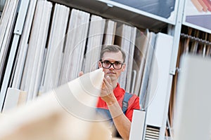 seller of the floor coverings store choosing the necessary samples of laminated boards .