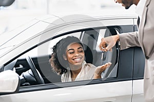 Seller Giving Lady Key For Test Drive In Dealership Showroom