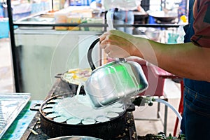 Seller holding a pot of Thai sweetmeat on the hot pan