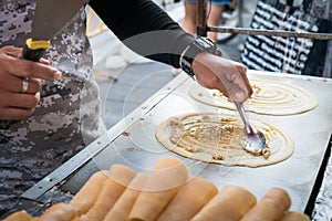Seller making Khanom Tokyo thin flat pancake Thai street snack