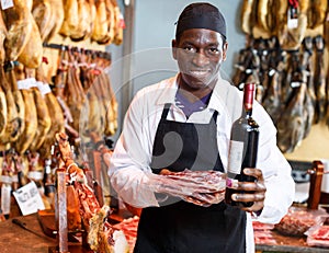 Seller offering wine to jamon