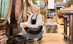 Seller pouring draft wine from wooden barrels