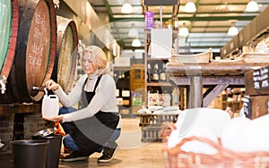 Seller pouring draft wine from wooden barrels