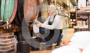 Seller pouring draft wine from wooden barrels