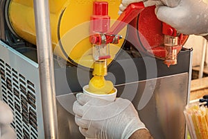 Seller pours frozen juice or serbet into a once-only glass from the machine.