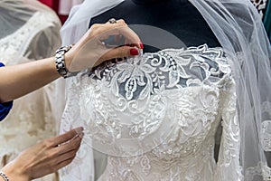 Seller`s hands correcting bridal veil on mannequin in salon