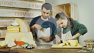 Sellers man and woman working together in a shop of cheeses