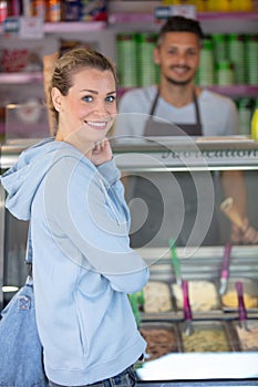 selling ice cream to young woman in pastry shop