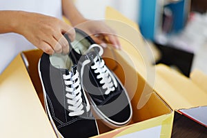 Selling online shopping / Woman packing shoes sneakers in cardboard box prepare parcel box to delivery service customer ecommerce