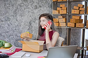 Selling products online. Young entrepreneur woman talking phone as she sits at her desk