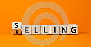Selling or telling symbol. Turned wooden cubes and changed the word `telling` to `selling`. Beautiful orange background, copy