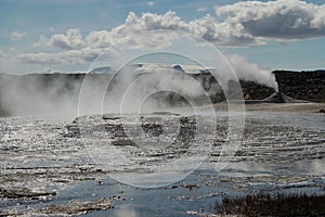 Seltun / Krysuvik KrÃ½suvÃ­k: Fumarole emit sulphur gas behind geothermal field with puddles of hot water