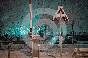 Semaphore or signal for oncoming train with barriers in night time. Grade crossing with lights and barriers in snowy weather at