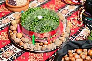 Semeni on plate with a white rose in the middle and, candles, bag of nuts on a tablecloth with national patterns and prints .