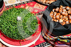 Semeni with a white rose in the middle and a bag of nuts on a tablecloth with national patterns and prints .