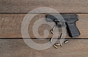 Semi-automatic 9mm pistol and bullets on wooden background with Copy Space