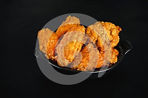 Semi-finished chicken wings on a dark background . Half-finished. Quick cooking at home. Fast food. Breaded chicken