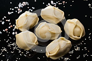 Semi-finished dumplings mantas on black background with salt