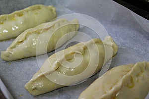 Semi-finished products, pies with filling are on baking paper in the oven