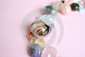 Semi-precious stones of different colors on a pink background. Amethyst, rose quartz, agate, apatite, aventurine, olivine,