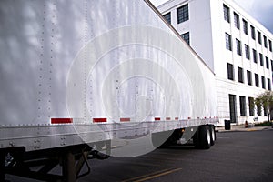 Semi trailer on city street with office building on background