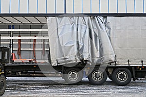 A semi-trailer with an exposed tarpaulin during unloading. Transport and unloading