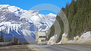 Semi-trailer truck drives along asphalt highway crossing Jasper National Park