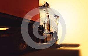 Semi Trailer Truck with Speeding Motion in the Sunset. Delivery Trucks Driving on the Road. Cargo Shipping. Diesel Truck Lorry