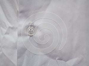 Semi transparent plastic button on white cotton shirt