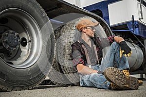 Semi Truck Driver Resting Next to His Truck