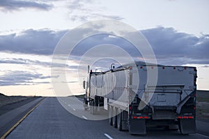 Semi truck with long bulk trailer on evening road
