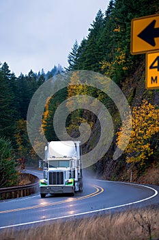 Semi truck in rain on windy autumn highway turn