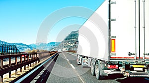 Semi truck speeding on empty highway line - Transport logistic concept with semitruck container driving on speedway - Focus on