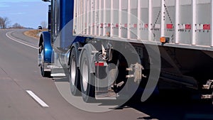 Semi truck and trailer driving on the freeway on a sunny day.