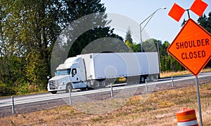 Semi truck trailer on highway and road sign