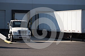 Semi truck and trailer standing in warehouse dock with loading g