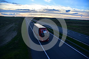 Semi truck transporting sea container on highway on sunset background. Shipping Containers Delivery, Maritime Services and