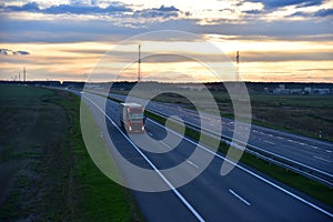 Semi truck transporting sea container on highway on sunset background. Shipping Containers Delivery, Maritime Services and