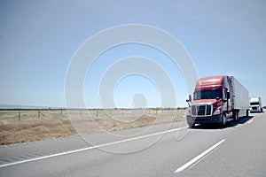 Semi trucks convoy on straight highway on flat plateau photo