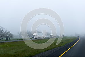 Semi trucks trailers big rigs cargo convoy on foggy highway