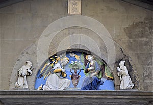 Semicircle containing a beautiful terracotta sculpture painted on the wall of a historic building in Florence.