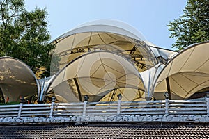 The semicircular brown roof of the fabric of the tents behind the fence