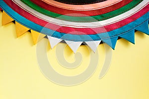 Semicircular handmade cloth stitched from colorful stripes on top of bright pastel yellow background.