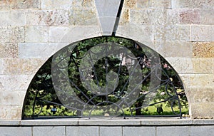Semicircular window in the stone-tiled wall was covered with a metal grating