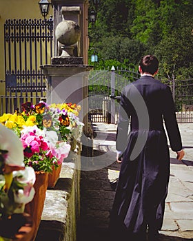 Seminarian walking past pots of blooming flowers