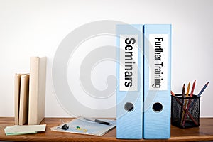 Seminars and Further Training binders in the office. Stationery on a wooden shelf