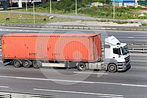 Semitrailer driving on highway with orange container